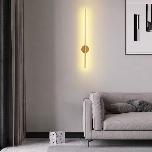 Modern rechargeable gold wall lamp in a living room setting with a gray sofa and neutral decor.