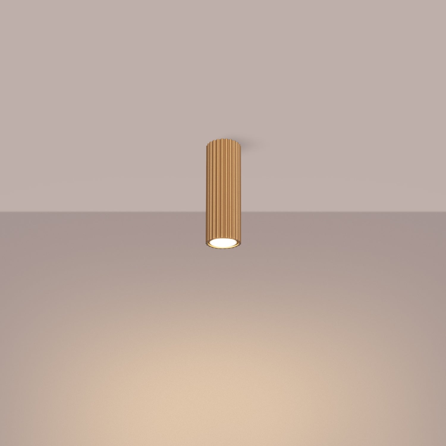 Gold Ribbed Tube Ceiling Spotlight 20cm switched on in modern UK home interior, warm LED glow