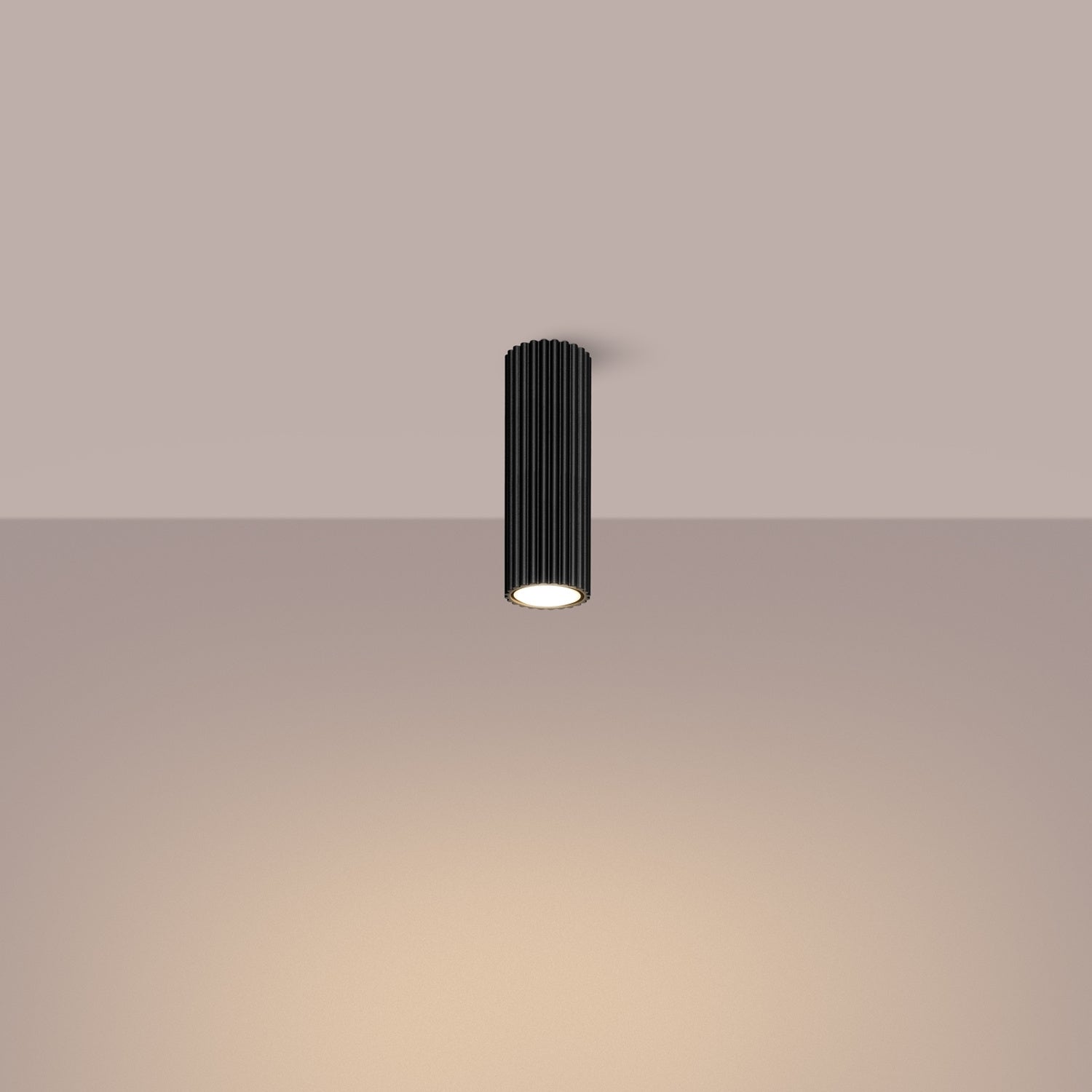 Black Ribbed Tube Ceiling Spotlight 20cm switched on in modern UK home interior, warm LED glow