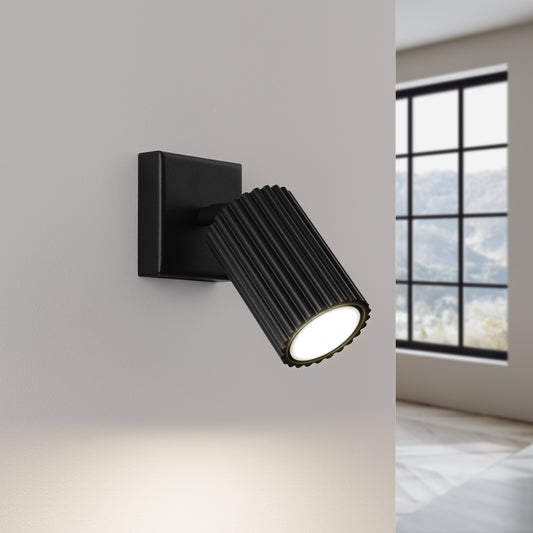 Black Ribbed Tube Wall Light switched on in modern UK home interior, warm LED glow