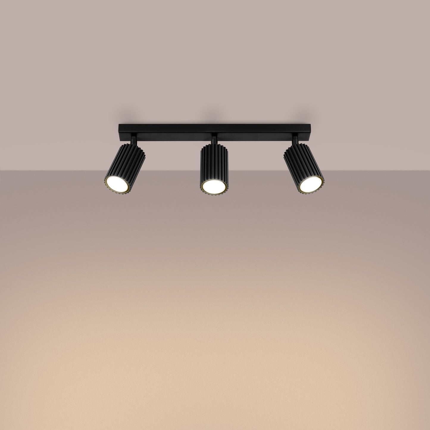 Black Triple Ribbed Spotlight Bar switched on in modern UK home interior, warm LED glow