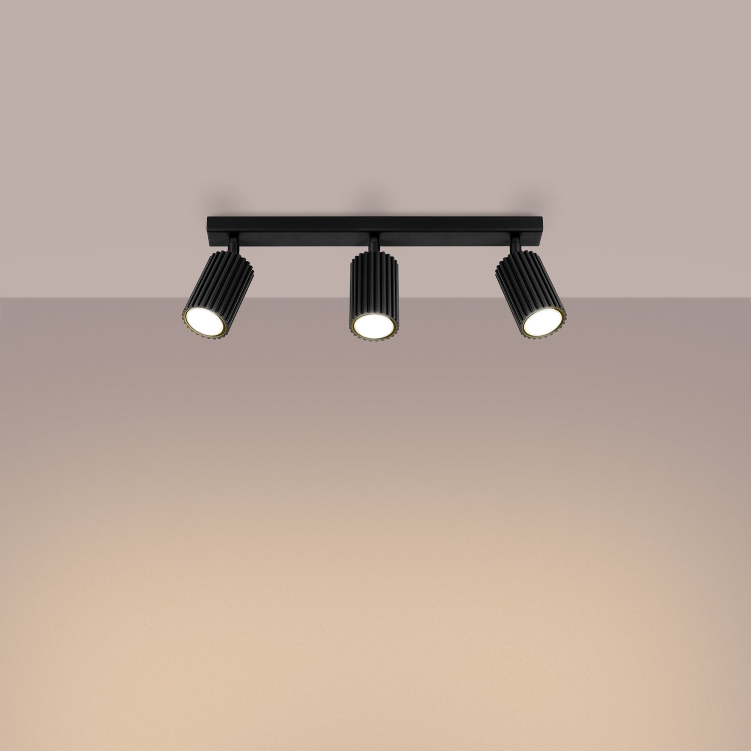 Black Triple Ribbed Spotlight Bar switched on in modern UK home interior, warm LED glow