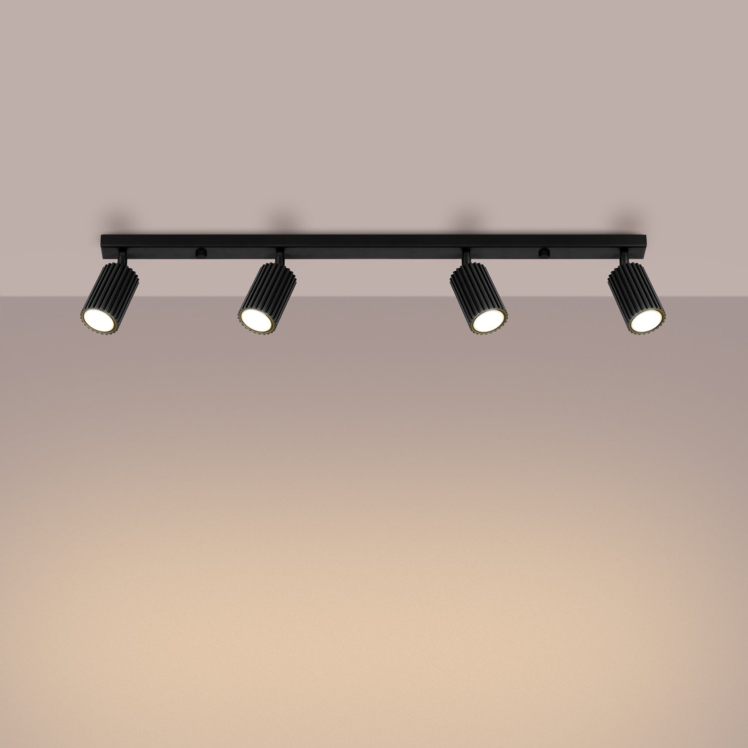 Black Four Light Ribbed Spotlight Bar switched on in modern UK home interior, warm LED glow