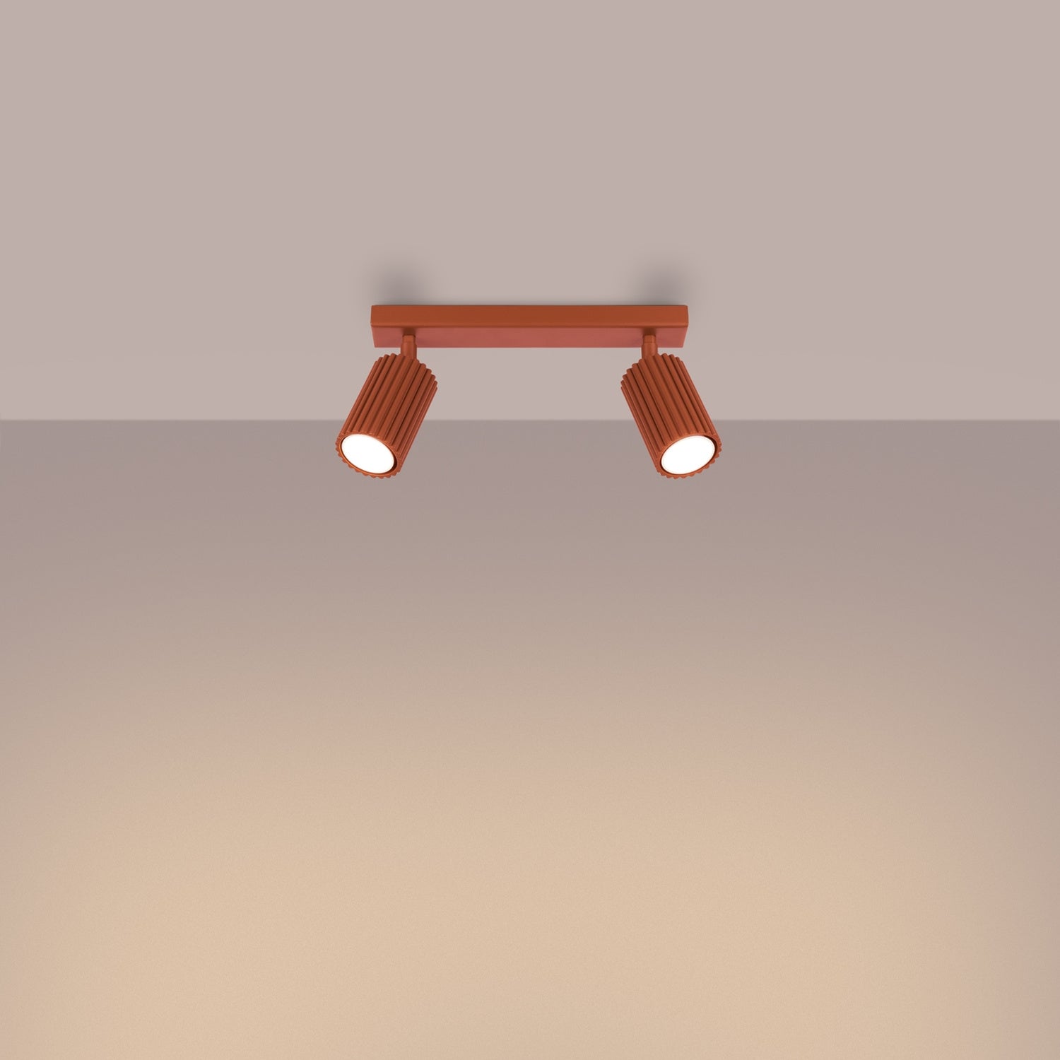 Red Ochre Twin Ribbed Surface Spotlight switched on in modern UK home interior, warm LED glow