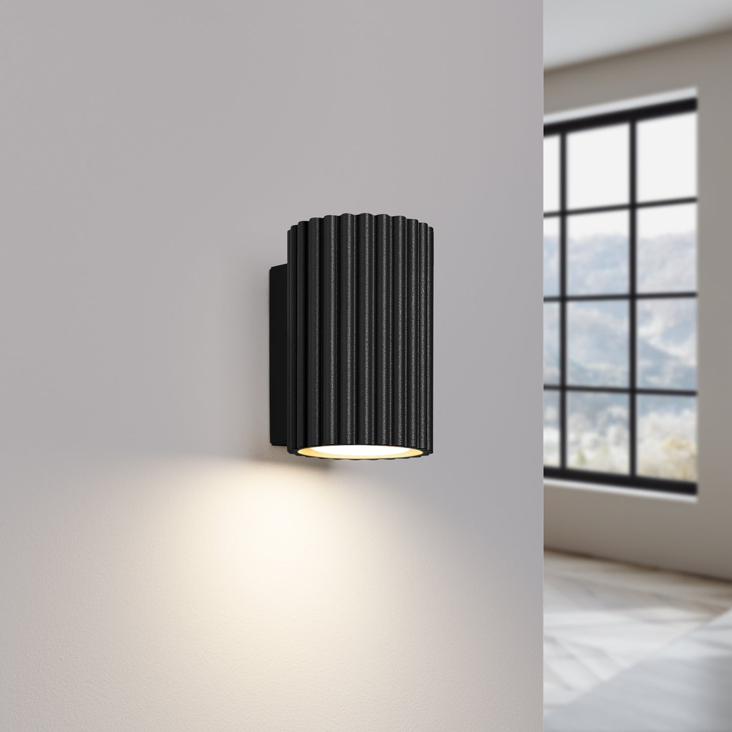 Black Mini Ribbed Cylinder Wall Light switched on in modern UK home interior, warm LED glow