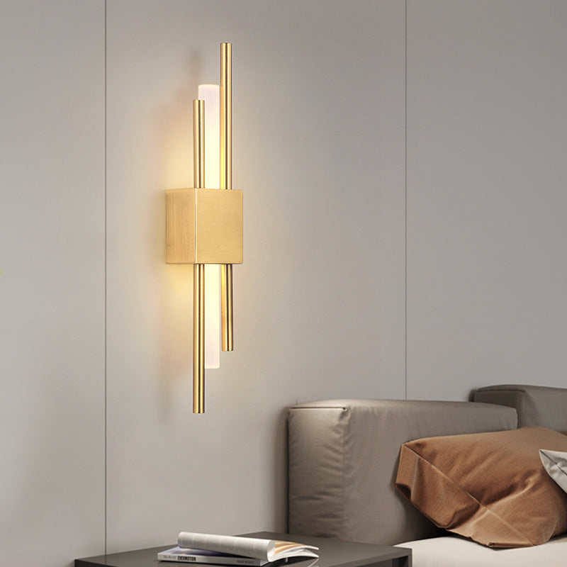 Modern gold wall sconce on a neutral wall with a sofa in the background