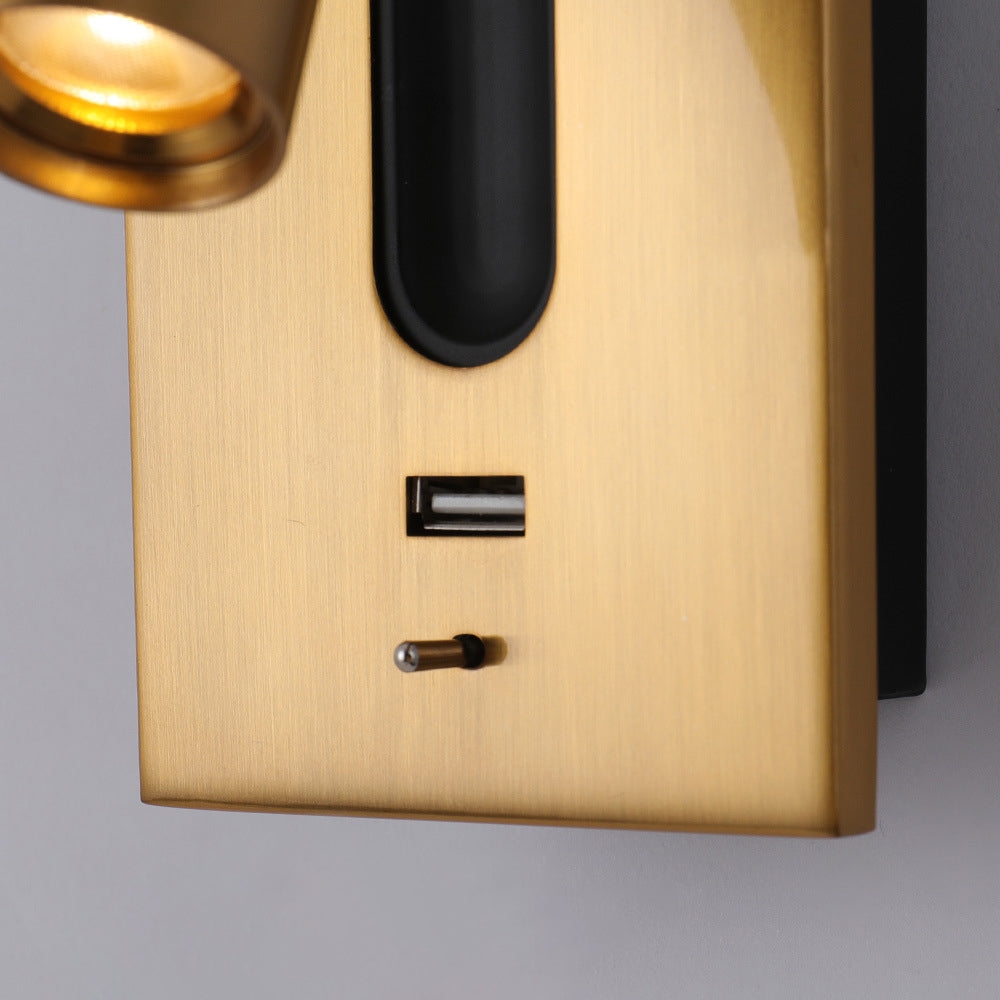 Close-up of a golden wall-mounted light fixture with a black shade on a gray background.